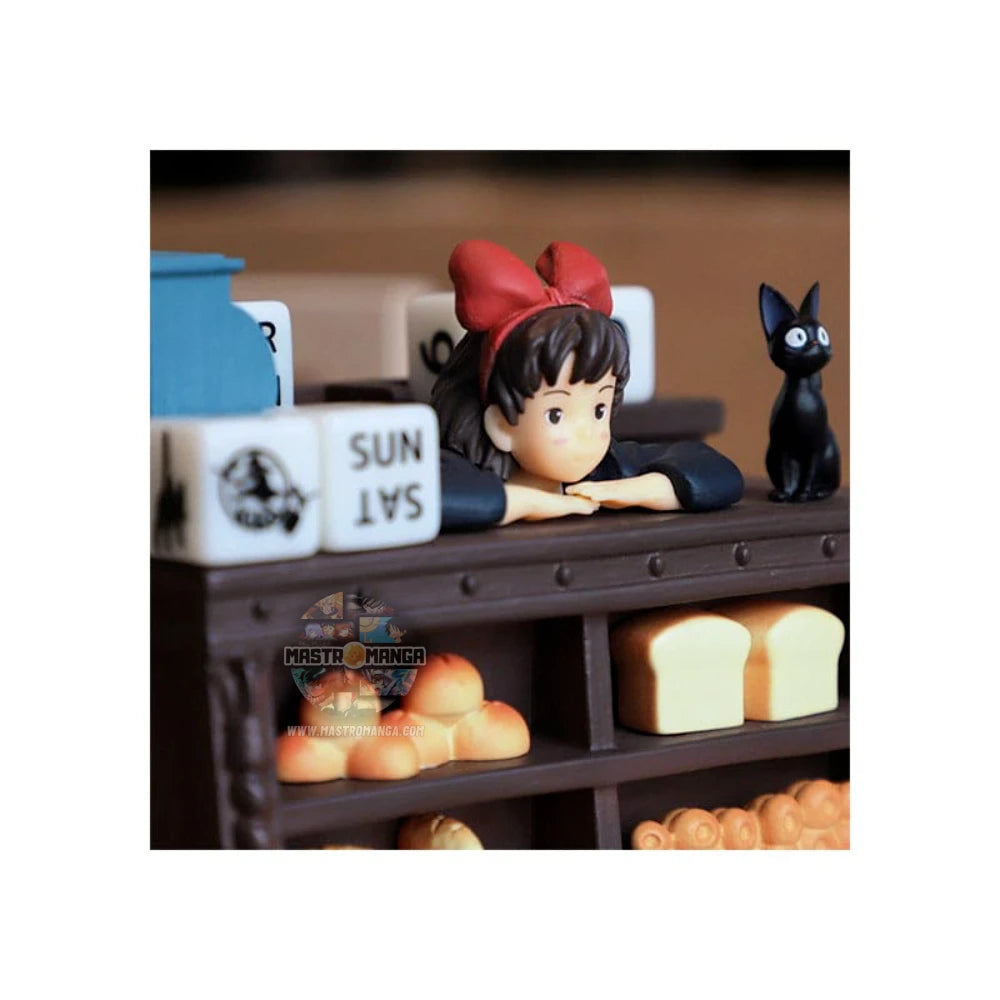 Calendario perpetuo ufficiale Studio Ghibli ispirato a Kiki - Consegne a domicilio, con Kiki in grembiule dietro il bancone del pane insieme al gatto Jiji e dadi per la data