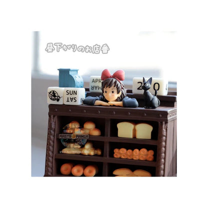 Calendario perpetuo ufficiale Studio Ghibli ispirato a Kiki - Consegne a domicilio, con Kiki in grembiule dietro il bancone del pane insieme al gatto Jiji e dadi per la data