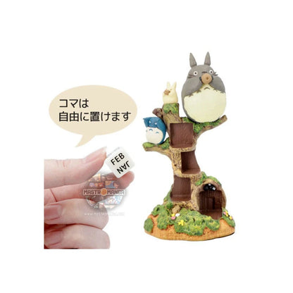 Calendario perpetuo ufficiale Studio Ghibli raffigurante il grande Totoro e i piccoli Totoro seduti su un tronco d'albero mentre suonano l'ocarina, con dadi numerati per la data