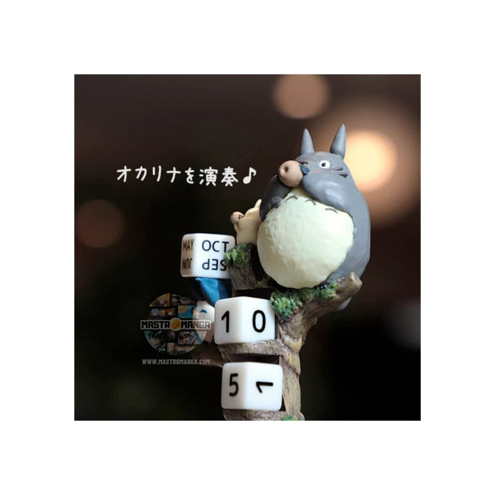 Calendario perpetuo ufficiale Studio Ghibli raffigurante il grande Totoro e i piccoli Totoro seduti su un tronco d'albero mentre suonano l'ocarina, con dadi numerati per la data